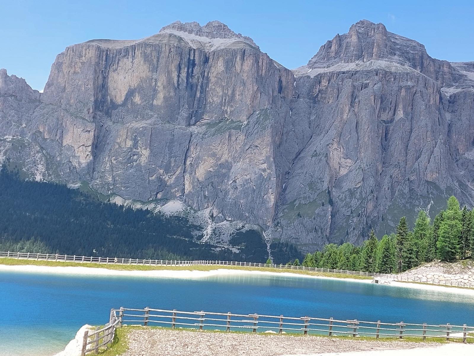 Un lago alpino dalle acque turchesi ai piedi delle pareti del Gruppo del Sella